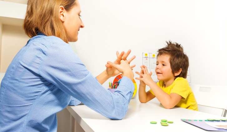 Boy exercises putting fingers with therapist